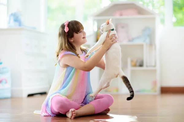 子供は家で猫と遊ぶ 子供とペット 可愛い白い猫の餌やりやペット リビングルームのインテリアで猫の木や傷 子供たちは子猫を遊びます ホーム動物 — ストック写真