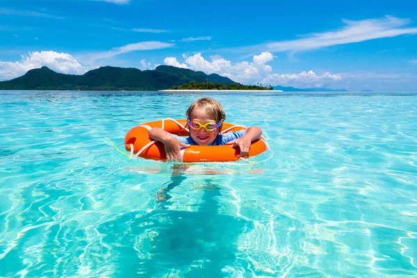 美しいビーチでインフレータブルリングを持つ子供 エキゾチックな海で泳いでいる男の子 子供と海の休暇 子供たちは夏のビーチで遊ぶ 水の楽しみ 子供たちは泳ぐ 熱帯島での家族の休日 — ストック写真