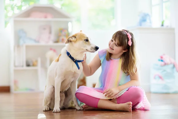 赤ちゃん犬と遊ぶ子供 子供は子犬と遊ぶ 家にいる小さな女の子と大きな犬 子供と友情 子供はペットと床に座っている 動物愛護 — ストック写真