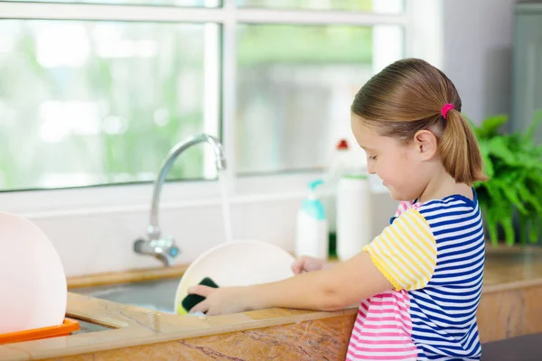 洗碗的孩子做家务活在窗前吃过午饭后 穿着白色厨房清洁盘子的孩子 — 图库照片