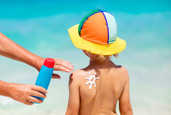 Mom applying sunscreen on child. Safe beach and sun tan fun. UV protection for young kid. Skin health care. Sun block spf cream and lotion for kids. Summer vacation with children.