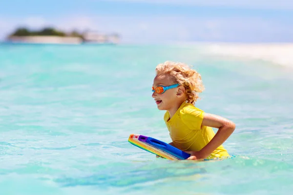 熱帯のビーチでサーフィンをする子供 アジアの家族の夏休み 子供たちは海水で泳ぐ サーフボードの子供だ エキゾチックな海で泳いでいる男の子 子供と一緒に旅行する 水とビーチスポーツ — ストック写真