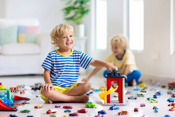 子供たちは白い部屋でおもちゃの車で遊ぶ 車やトラックのおもちゃで遊んでいる小さな男の子 子供のための車両や輸送ゲーム 駐車場のある子供 家庭や保育園で遊ぶ子供たち — ストック写真