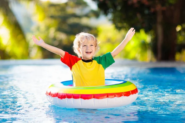 子供のプールおもちゃのリングに浮かんでいます 子供たちは泳ぐ 子供のためのカラフルな虹のフロート トロピカルリゾートで家族の夏休みを楽しんでいる小さな男の子 ビーチや水のおもちゃ 太陽の保護 — ストック写真