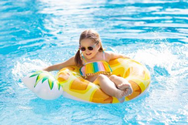 Şişme ananas yüzüklü çocuk yüzme havuzunda yüzüyor. Küçük kız yüzmeyi ve tropikal tatil köyü havuzuna dalmayı öğreniyor. Çocuklarla yüzmek. Çocuklar için sağlıklı bir spor. Su eğlencesi