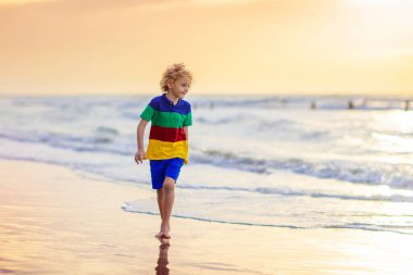 Okyanus sahilinde oynayan bir çocuk. Gün batımında dalgalara atlayan bir çocuk. Aile için deniz tatili. Yaz tatili boyunca egzotik adada koşan küçük çocuk.. 