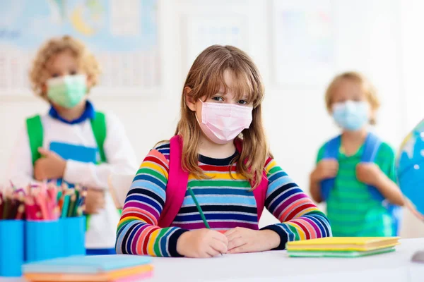 School child wearing face mask during corona virus and flu outbreak. Boy and girl going back to school after covid-19 quarantine and lockdown. Group of kids in masks for coronavirus prevention.