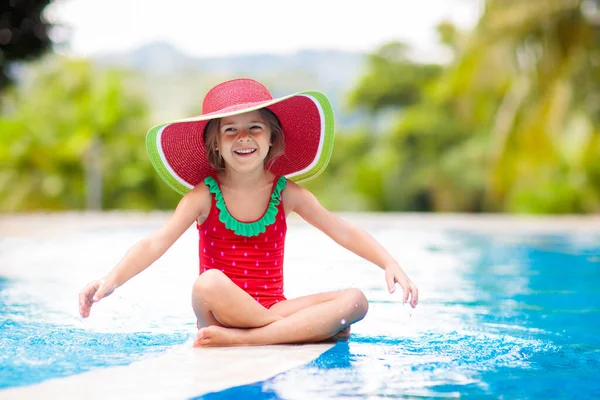 在游泳池里的孩子有孩子的家庭的热带假期 小女孩身穿红色泳衣 头戴西瓜太阳帽 在异国情调的海岛度假胜地的室外游泳池里嬉戏 为孩子们提供水和游泳的乐趣 — 图库照片
