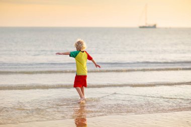 Okyanus sahilinde oynayan bir çocuk. Gün batımında dalgalara atlayan bir çocuk. Aile için deniz tatili. Yaz tatili boyunca egzotik adada koşan küçük çocuk.. 