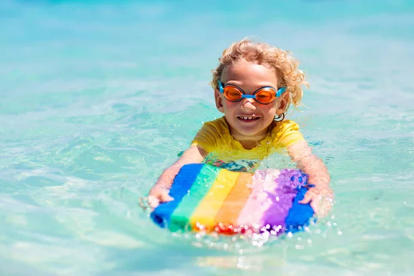 熱帯のビーチでサーフィンをする子供 アジアの家族の夏休み 子供たちは海水で泳ぐ サーフボードの子供だ エキゾチックな海で泳いでいる男の子 子供と一緒に旅行する 水とビーチスポーツ — ストック写真