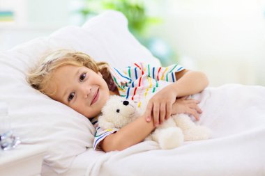 Astım ilacıyla hasta küçük bir çocuk. Hasta çocuk yatakta yatıyor. Öksürük tedavisi için spreyi olan hasta bir çocuk. Grip mevsimi. Genç hastalar için yatak odası ya da hastane odası. Sağlık ve İlaç Hizmetleri.