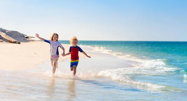 孩子们在热带海滩玩耍 孩子们在暑假时在海上游泳和玩耍 沙子和水的乐趣 防晒幼儿 小男孩和小女孩在海滨跑来跑去 — 图库照片