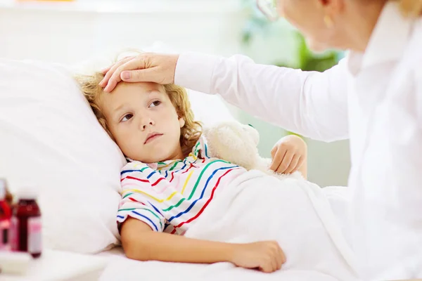 生病的小男孩与药物 妈妈在床上检查生病孩子发烧的情况 带吸入器的病童用于哮喘咳嗽治疗 流感季节 年幼病人的家长在卧室或病房 — 图库照片