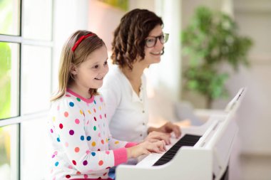 Piyano çalan çocuk. Çocuklar müzik çalar. Çocuklar için klasik eğitim. Sanat dersi. Beyaz dijital klavyede küçük bir kız. Genç öğrenciler için bir araç. Okulda ya da evde müzik dersi.