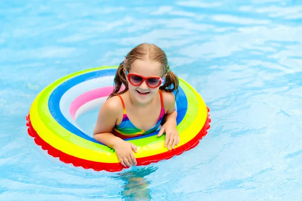 子供のプールおもちゃのリングに浮かんでいます 子供たちは泳ぐ 子供のためのカラフルな虹のフロート トロピカルリゾートで家族の夏休みを楽しんでいる小さな女の子 ビーチや水のおもちゃ 太陽の保護 — ストック写真