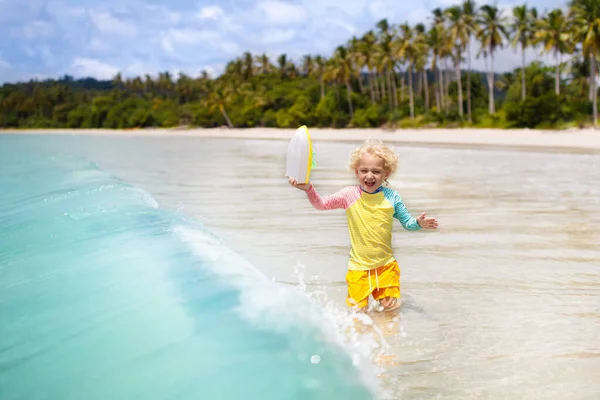 美しいビーチで子供 おもちゃのボートが走って海の海岸でジャンプしている小さな男の子 子供と海の休暇 子供たちは夏のビーチで遊ぶ 水の楽しみ 子供たちは泳ぐ 熱帯島での家族の休日 — ストック写真