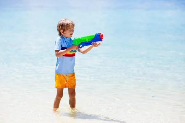 おもちゃの水銃で遊ぶ子供 休暇とビーチの楽しみ 子供たちは熱帯の島のリゾートでプラスチック製のピストルで走り 海での家族の夏の休暇の活動 子供との旅行 — ストック写真