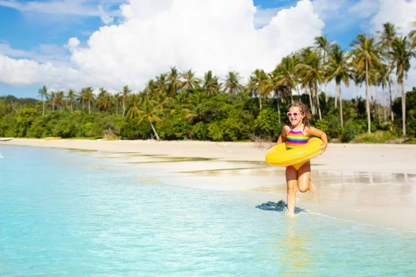 熱帯のビーチで遊んでいる子供 海の海岸でインフレータブルフロートリングを持つ少女 家族の夏休み 子供たちは水と砂のおもちゃで遊ぶ 水泳の楽しみ 若い子供たちと一緒に旅行する アジアの休日 — ストック写真