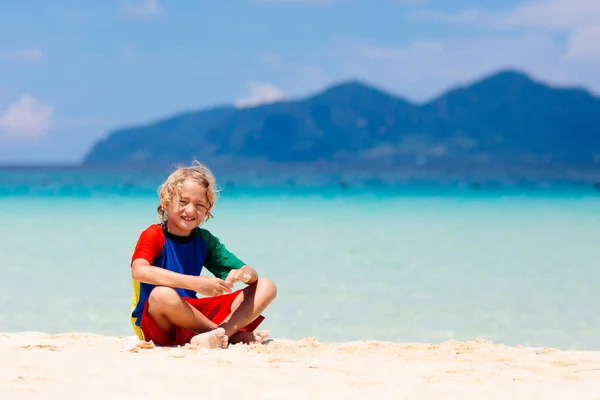 熱帯のビーチで遊んでいる子供たち 子供たちは夏休みに海で泳いだり遊んだりします 砂と水の楽しさ 幼い子供のための太陽の保護 小さな男の子と女の子が走って海の海岸でジャンプします — ストック写真