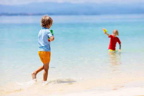 孩子们玩玩具水枪 度假和海滩的乐趣 热带岛屿度假胜地的孩子们在跑步和玩塑料手枪 家庭暑期海上活动 与子女一起旅行 — 图库照片