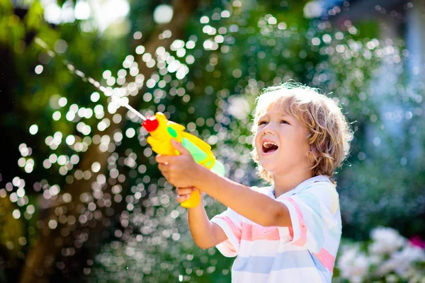 孩子们在花园里玩水枪玩具 户外夏天的乐趣 小男孩在阳光灿烂的后院玩水管 儿童派对游戏 健康的活动为炎热的晴天 — 图库照片