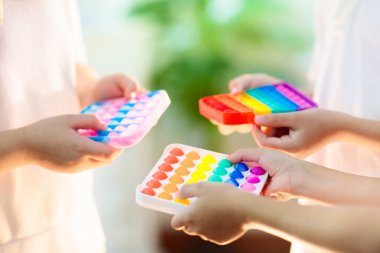 Çocuklar duyusal oyuncaklarla oynarlar. Stres ve endişe giderici. Stresli çocuklar ve yetişkinler için son moda silikon hareketlendirme oyunu. Yumuşak, yumuşak baloncuk oyuncakları. Çocuk gökkuşağı renginde pop-it ile oynuyor.