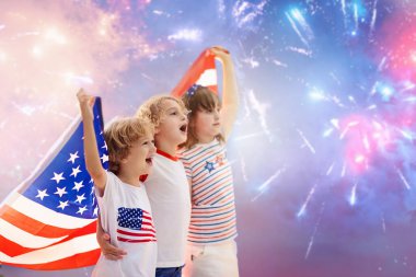 Amerikan ailesi 4 Temmuz 'u kutluyor. Independence Day havai fişeklerini izleyen insanlar Amerikan bayrağı taşıyor. Gururlu Amerikan çocukları tezahürat ve kutlama yapıyor. Amerikan sembollü çocuk. Ulusal bayram partisi.