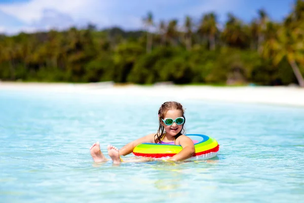Child with inflatable ring on beautiful beach. Little girl swimming in exotic sea. Ocean vacation with kid. Children play on summer beach. Water fun. Kids swim. Family holiday on tropical island.
