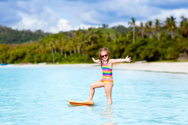 熱帯のビーチでサーフィンをする子供 アジアの家族の夏休み 子供たちは海水で泳ぐ サーフボードの子供だ エキゾチックな海で泳いでいる少女 子供と一緒に旅行する 水とビーチスポーツ — ストック写真