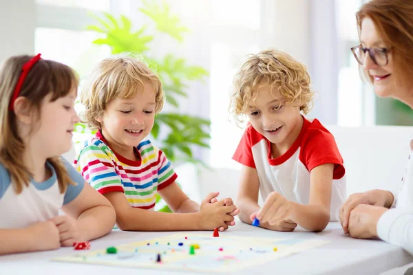 家庭でボードゲームをプレイ家族 子供たちは戦略ゲームをプレイ 小さな男の子がサイコロを投げる 夏休みのための楽しい屋内活動 兄弟の絆だ 教育用玩具 友達はゲームを楽しむ夜 — ストック写真