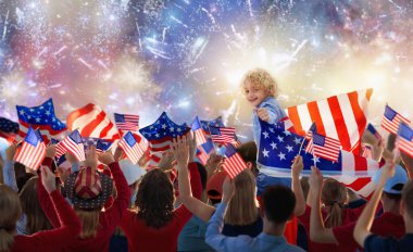 Amerikan ailesi 4 Temmuz 'u kutluyor. Independence Day havai fişeklerini izleyen insanlar Amerikan bayrağı taşıyor. Gururlu ABD kalabalığı tezahürat ve kutlama yapıyor. Amerikan sembollü bir grup. Ulusal bayram partisi.