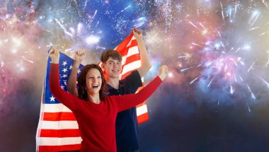 Amerikan ailesi 4 Temmuz 'u kutluyor. Independence Day havai fişeklerini izleyen insanlar Amerikan bayrağı taşıyor. Gururlu ABD taraftarları tezahürat ve kutlama yapıyor. Amerika sembollü genç bir çift. Ulusal bayram partisi.