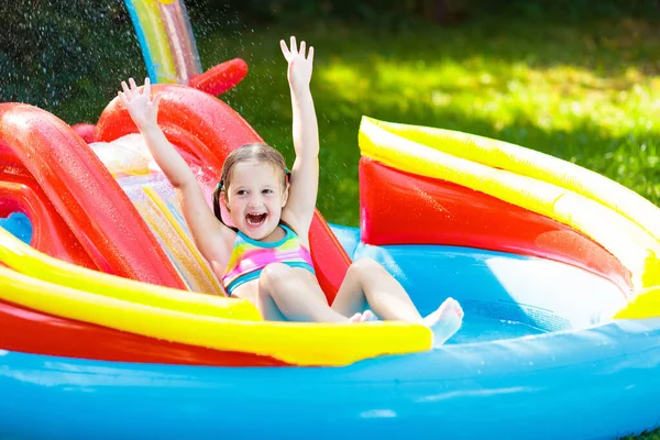 수영장에서 아이들 아이들은 슬라이드 그리고 물장구를 여름날 장난감을 가지고 미끄러지면서 — 스톡 사진