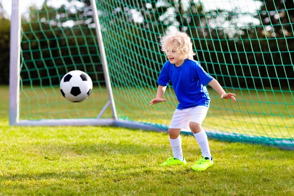 孩子们在户外运动场踢足球 孩子们在足球比赛中进了一球 小男孩在踢球 穿着队服和紧身衣跑步的孩子 学校足球俱乐部 对年轻运动员的体育培训 — 图库照片
