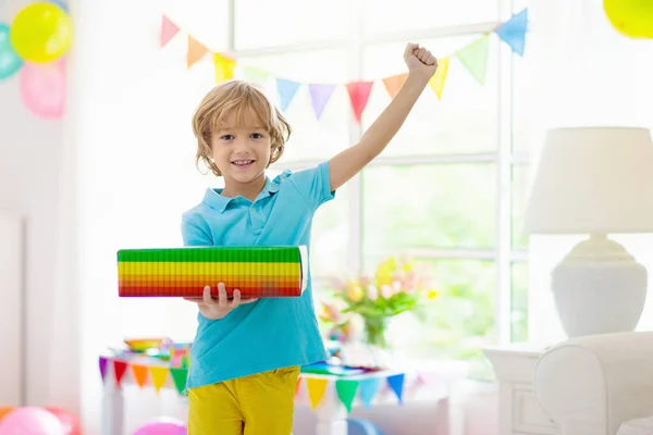 子供の誕生日パーティー ケーキにろうそくを吹いてプレゼントを開く子 パステル虹のテーマのお祝い 家でお祝いする家族 男の子の贈り物を開くと ケーキを食べる 子供用お菓子 — ストック写真