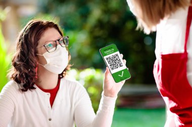 Cep telefonundaki dijital covid-19 aşı sertifikası. Coronavirus aşılanmış insanlar restoran girişindeki QR kodunu tarıyor. Negatif test, tamamlanmış aşı ve güvenli yolculuk için dokunulmazlık.