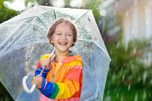 秋の雨の中で遊ぶ子供 傘を持ってる子供 秋の季節に公園を走る少年 どんな天気でも子供のための屋外の楽しみ 子供のための雨防水摩耗 ブーツやジャケット — ストック写真