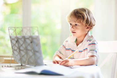 Çocuk evde ödevini yapıyor. Çevrimiçi uzaktan öğrenme. Bilgisayarlı okul çocukları öğretmen ve sınıf grubuyla görüntülü konuşma yapıyorlar. Koronavirüs salgınında evde eğitim.