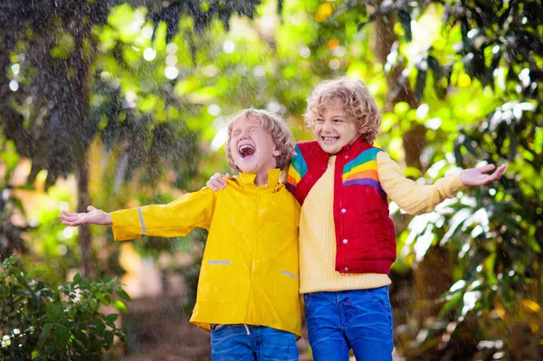 秋の雨の中で遊ぶ子供 傘を持ってる子供 秋の季節に公園を走る少年 どんな天気でも子供のための屋外の楽しみ 子供のための雨防水摩耗 ブーツやジャケット — ストック写真