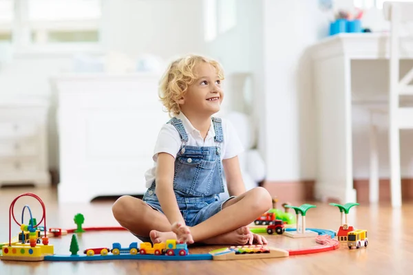 孩子们玩木制铁路 玩玩具火车的孩子幼儿教育玩具 小男孩在家里或幼儿园的白色地板上建造铁路轨道 可爱的孩子玩汽车和引擎 — 图库照片