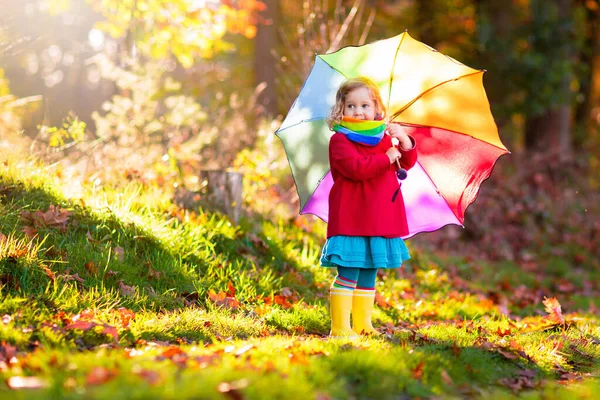 孩子在雨中玩耍 带着雨伞和雨靴的孩子们在秋雨中户外玩耍 小女孩在泥泞的水坑里跳跃 孩子们被秋天的雨天逗乐了 在暴风雨中奔跑的孩子 — 图库照片