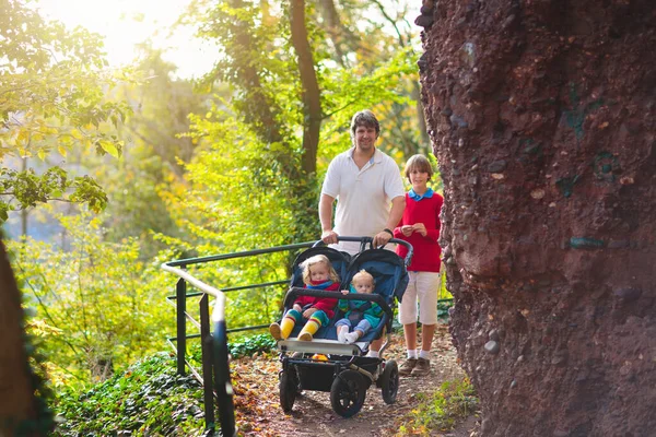 带着双人推椅远足的人 爸爸和孩子们在散步 与幼儿一起进行健康的户外活动 与新生儿和幼儿一起运动和锻炼 爸爸和孩子在公园里远足 — 图库照片