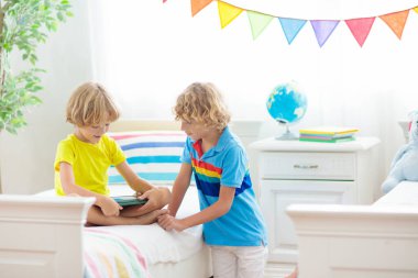 Tablet bilgisayarı olan çocuk. Çocuklar çevrimiçi çalışıyor. İki kardeş için yatak odası. Evde öğrenme ve öğrenme için elektronik cihaz. Bilgisayarlı küçük çocuk. Çocuklar için Gadget ekran zamanı. Evdeki çocuk.. 