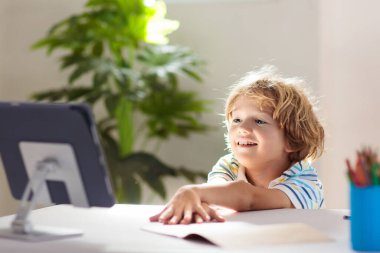 Çevrimiçi uzaktan öğrenme. Bilgisayarlı okul çocukları öğretmen ve sınıf grubuyla görüntülü konuşma yapıyorlar. Çocuk evden ders çalışıyor. Karantina ve koronavirüs salgını sırasında evde eğitim.