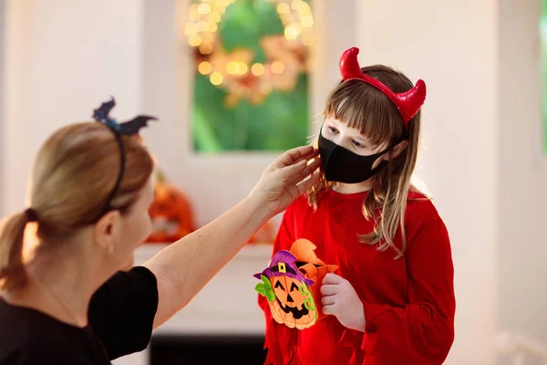 孩子们穿着万圣节服装 戴着面具 捉弄或招待 儿童和母亲穿着糖果桶在大流行病中的流行 小女孩戏弄或用南瓜灯来招待 秋节假期快乐 — 图库照片