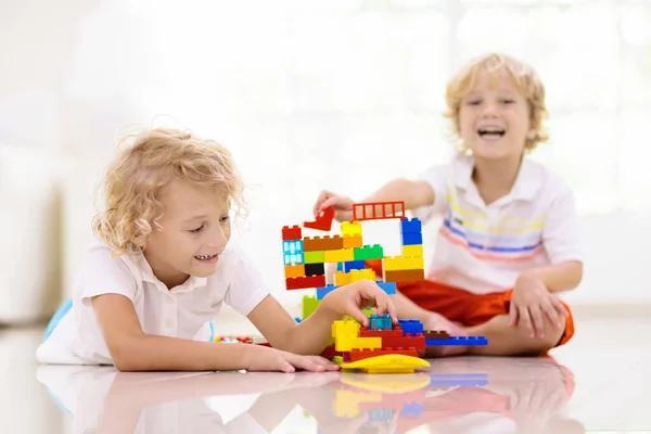 孩子们玩五颜六色的玩具块 孩子们玩塑料砖 小男孩在建造塔楼和宇宙飞船 儿童教育玩具 幼儿园或幼儿园的教室 孩子在家里 — 图库照片