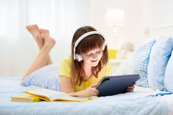 10代の少女でタブレットPcを持ってる 十代の子供のテキストメッセージとオンラインゲームをプレイ ソーシャルメディアでメッセージを送る小学生 遠隔学習のための宿題をしている白い寝室の前の子供 ビデオチャット — ストック写真