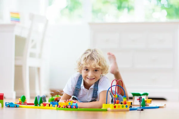 孩子们玩木制铁路 玩玩具火车的孩子幼儿教育玩具 小男孩在家里或幼儿园的白色地板上建造铁路轨道 可爱的孩子玩汽车和引擎 — 图库照片