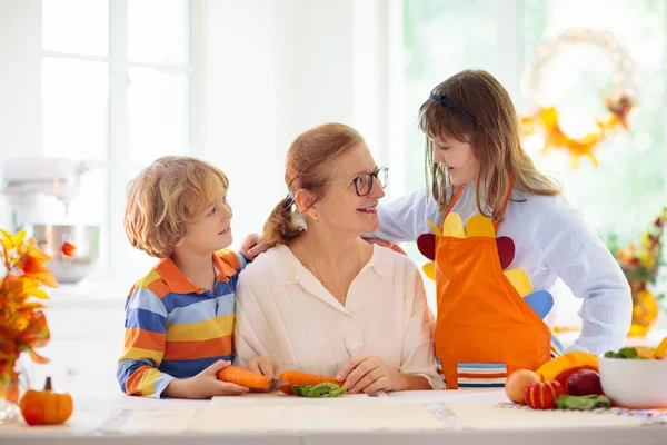 家庭做饭感恩节晚餐 奶奶和孩子在装饰过的厨房切南瓜 妈妈和孩子在秋天做蔬菜餐 祖父母来访 秋季食品 — 图库照片