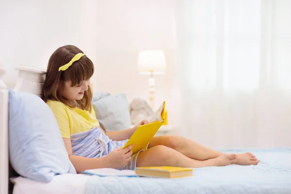 一个在床上看书的少女 孩子们读书 小学生在远程学习班做作业 幼儿的教育 学生从家里学习 十几岁以下儿童的白色卧室 — 图库照片